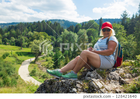 Smiling senior woman taking a selfie while hiking in the mountains 128421640