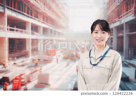 A young woman wearing work clothes working at a building construction site 128422226