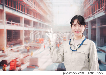 A young woman wearing work clothes working at a building construction site 128422227