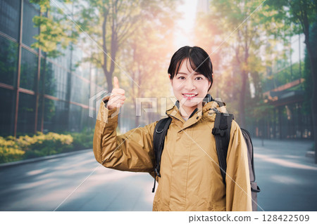 A young female office worker wearing a raincoat commuting to work 128422509