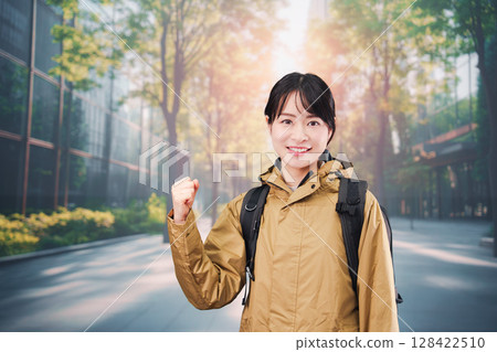A young female office worker wearing a raincoat commuting to work 128422510