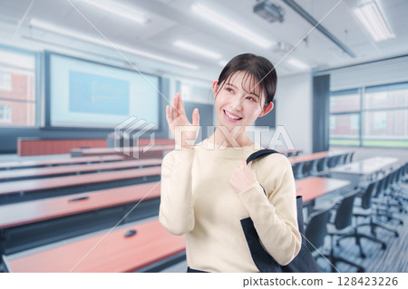 一名年輕的女大學生走進大學教室 一名年輕的女大學生走進大學教室 128423226