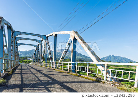 "Kaizegawa Bridge" in Minamiaso Village with the blue sky and the five peaks of Mt. Aso in the background. A bridge in the shade of the river in Minamiaso Village. "Kaizegawa Bridge" in Minamiaso Village with the blue sky and the five peaks of Mt. Aso in the background. A bridge in the shade of the river in Minamiaso Village. 128423296