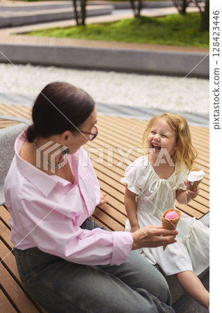 Grandmother and granddaughter enjoying ice cream at park Grandmother and granddaughter enjoying ice cream at park 128423446
