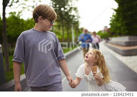 Slow and sweet. Children lead grandparents during family walk with ice cream 128423451