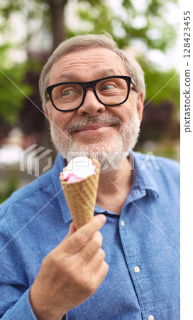 Flavors that last. Elderly man holding ice cream cone and smiling with joy 128423455