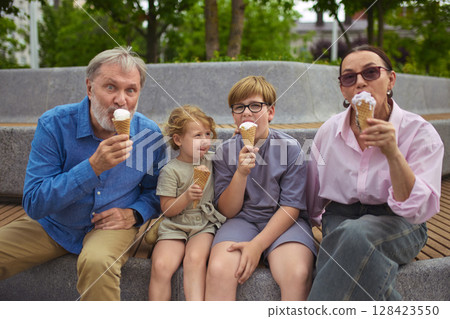 Timeless taste. Grandparents and children eating ice cream together outdoors Timeless taste. Grandparents and children eating ice cream together outdoors 128423550