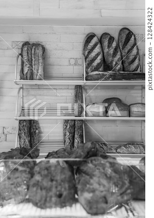 Bread, baguettes, different shapes and sizes lie on the shelves. Black and white vertical photo 128424322