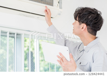 A male worker checks the operation of an air conditioner. 128424441