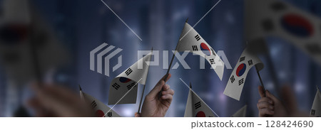 South Korean flags in their hands on a blurred urban background South Korean flags in their hands on a blurred urban background 128424690
