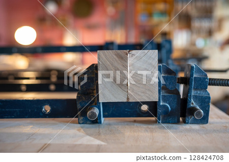 Beams glued tightly compressed with clamps in workshop for solid wooden panel for day. Wood assembly Beams glued tightly compressed with clamps in workshop for solid wooden panel for day. Wood assembly 128424708