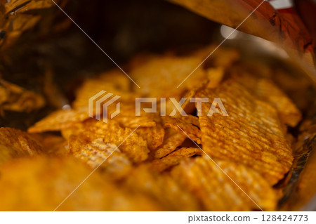 Overhead perspective inside a vibrant, crinkled bag reveals delicious, textured potato chips, emphasizing crunchy, savory flavor, ideal for indulgent, casual snacking moments Overhead perspective inside a vibrant, crinkled bag reveals delicious, textured potato chips, emphasizing crunchy, savory flavor, ideal for indulgent, casual snacking moments 128424773