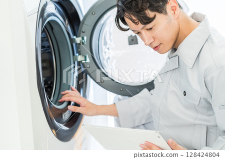 一名男工人檢查洗衣機的運作。 128424804