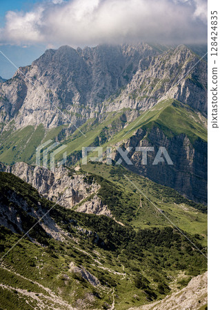 Rugged Alpine Peaks And Verdant Valleys In The Grigna Massif: Scenic Mountain Landscape In Lombardy Region Of Northern Italy Near Lake Como Rugged Alpine Peaks And Verdant Valleys In The Grigna Massif: Scenic Mountain Landscape In Lombardy Region Of Northern Italy Near Lake Como 128424835