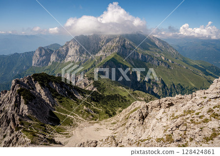 Rugged Alpine Peaks And Verdant Valleys In The Grigna Massif: Scenic Mountain Landscape In Lombardy Region Of Northern Italy Near Lake Como Rugged Alpine Peaks And Verdant Valleys In The Grigna Massif: Scenic Mountain Landscape In Lombardy Region Of Northern Italy Near Lake Como 128424861