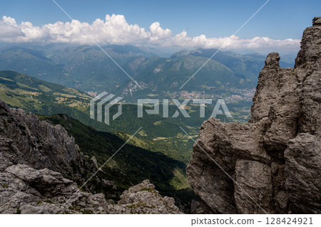 Rugged Alpine Peaks And Verdant Valleys In The Grigna Massif: Scenic Mountain Landscape In Lombardy Region Of Northern Italy Near Lake Como Rugged Alpine Peaks And Verdant Valleys In The Grigna Massif: Scenic Mountain Landscape In Lombardy Region Of Northern Italy Near Lake Como 128424921