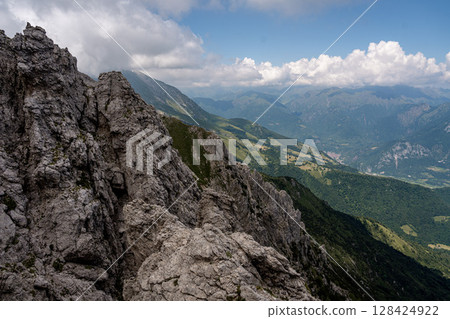 Rugged Alpine Peaks And Verdant Valleys In The Grigna Massif: Scenic Mountain Landscape In Lombardy Region Of Northern Italy Near Lake Como Rugged Alpine Peaks And Verdant Valleys In The Grigna Massif: Scenic Mountain Landscape In Lombardy Region Of Northern Italy Near Lake Como 128424922