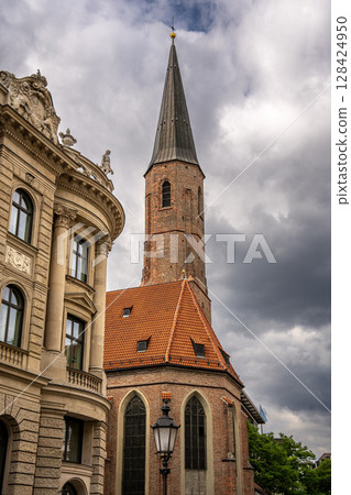 Historic St. Jakobs Church in Munich Near Sendlinger Tor: Elegant Gothic Architecture with Tall Steeple and Red Roof Surrounded by Classic Bavarian Buildings under Dramatic Cloudy Sky Historic St. Jakobs Church in Munich Near Sendlinger Tor: Elegant Gothic Architecture with Tall Steeple and Red Roof Surrounded by Classic Bavarian Buildings under Dramatic Cloudy Sky 128424950