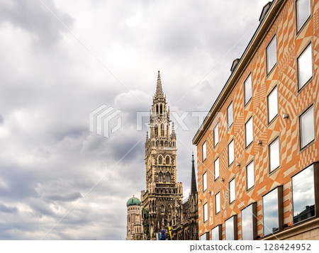 Iconic New Town Hall Tower In Munich With Ornate Gothic Architecture: Majestic Landmark Rising Behind Colorful Facade Near Marienplatz In The Historic City Center Of The Bavarian Capital Iconic New Town Hall Tower In Munich With Ornate Gothic Architecture: Majestic Landmark Rising Behind Colorful Facade Near Marienplatz In The Historic City Center Of The Bavarian Capital 128424952