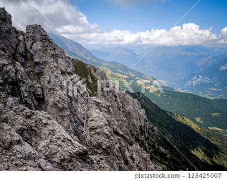 Rugged Alpine Peaks And Verdant Valleys In The Grigna Massif: Scenic Mountain Landscape In Lombardy Region Of Northern Italy Near Lake Como Rugged Alpine Peaks And Verdant Valleys In The Grigna Massif: Scenic Mountain Landscape In Lombardy Region Of Northern Italy Near Lake Como 128425007