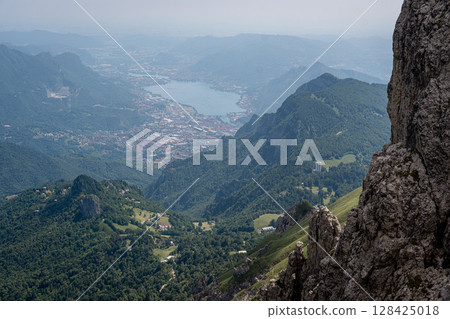 Rugged Alpine Peaks And Verdant Valleys In The Grigna Massif: Scenic Mountain Landscape In Lombardy Region Of Northern Italy Near Lake Como Rugged Alpine Peaks And Verdant Valleys In The Grigna Massif: Scenic Mountain Landscape In Lombardy Region Of Northern Italy Near Lake Como 128425018