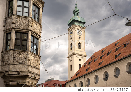 Historic Church Of The Holy Spirit In Munich: Elegant Baroque Architecture With Tower And Facade Near Marienplatz Under Dramatic Cloudy Sky 128425117