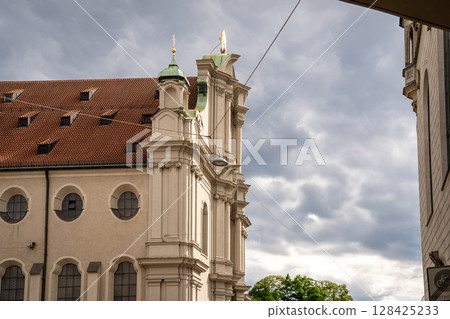 Historic Church Of The Holy Spirit In Munich: Elegant Baroque Architecture With Tower And Facade Near Marienplatz Under Dramatic Cloudy Sky Historic Church Of The Holy Spirit In Munich: Elegant Baroque Architecture With Tower And Facade Near Marienplatz Under Dramatic Cloudy Sky 128425233