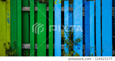 Vibrant Green And Yellow Wooden Fence With Vertical Slats: Playful Outdoor Pattern And Background With Natural Elements 128425277