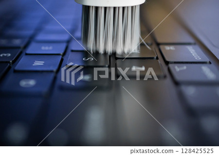 White cleaning brush sweeping across a laptop keyboard, symbolizing essential electronic device maintenance, ensuring longevity and efficient digital workflow for users White cleaning brush sweeping across a laptop keyboard, symbolizing essential electronic device maintenance, ensuring longevity and efficient digital workflow for users 128425525
