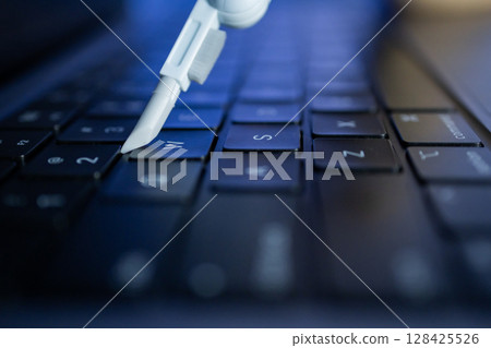 Precision cleaning tool for electronics precisely targets a laptop keyboard, symbolizing essential digital hygiene and device maintenance Precision cleaning tool for electronics precisely targets a laptop keyboard, symbolizing essential digital hygiene and device maintenance 128425526