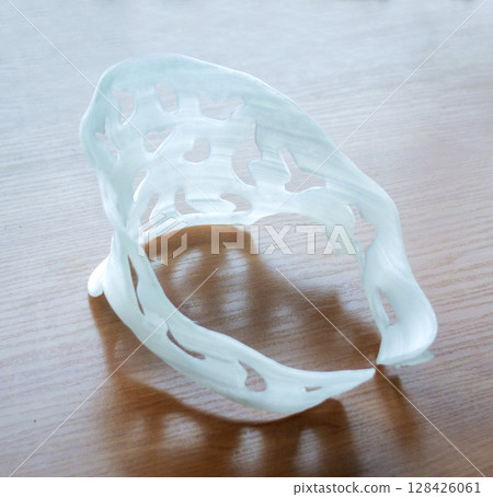 Medical plastic orthosis fixator overlay created on 3D printer. Neck splint plastic corset prosthesis langet printed on 3D printer from molten plastic. New modern medical 3D printing technology 128426061