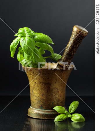 Vintage brass mortar with sprig of basil. 128426158