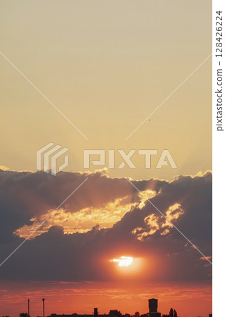 Beautiful sunset in the city with clouds and sun rays. The sun sets over the city. Beautiful sunset in the city with clouds and sun rays. The sun sets over the city. 128426224