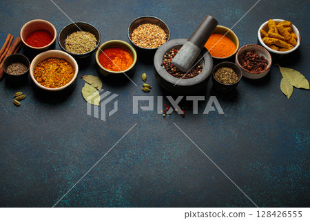 Mortar and pestle surrounded by colorful spices on dark background with copy space Mortar and pestle surrounded by colorful spices on dark background with copy space 128426555