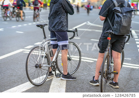 Cyclists. Two men in sportswear standing with bicycles on wide city street during urban cycling event. Concept of fitness, recreation, sport lifestyle 128426785