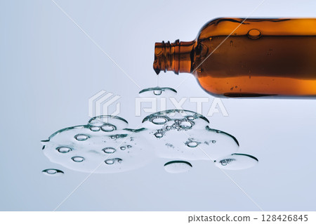 An open bottle with the serum leaking out of it. View from below. 128426845