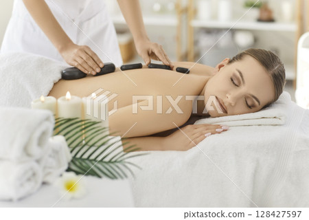 Masseuse Performing Stone Massage In Spa Salon 128427597