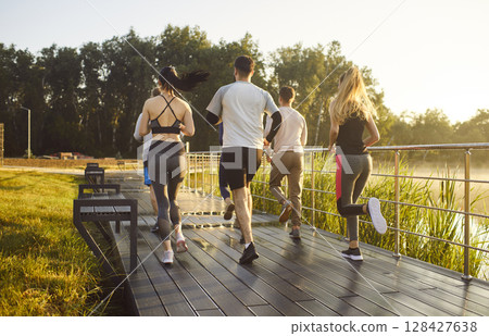 Back view of a team of young people running together in summer park having sport workout outdoors Back view of a team of young people running together in summer park having sport workout outdoors 128427638