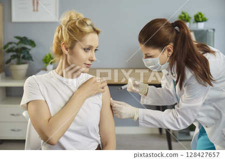 Vaccine injection into arm of young woman patient in hospital, immunization for disease prevention Vaccine injection into arm of young woman patient in hospital, immunization for disease prevention 128427657