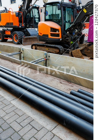 New modern insulated urban pipeline installation construction site  exposed underground pipes in shored trenches. Insulated steel pipes lie connection engineering infrastructure upgrade work 128427870