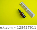 Cosmetic bottle and comb. Beauty salon, personal care products. Background with copy space. 128427911