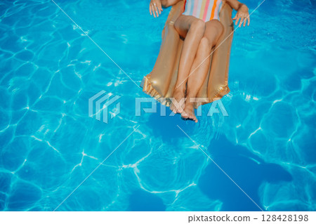 Top view of legs on floating bed in swimming pool. 128428198