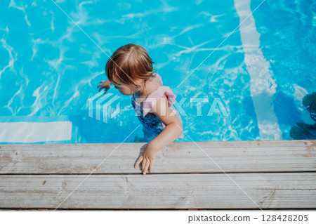 Little girl playing in shallow water in pool. Little girl playing in shallow water in pool. 128428205
