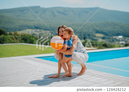 Little child and mother enjoying outdoor playtime with inflatable ball 128428212