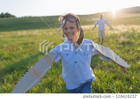 Child playing aviator in nature with wings and goggles. 128428237