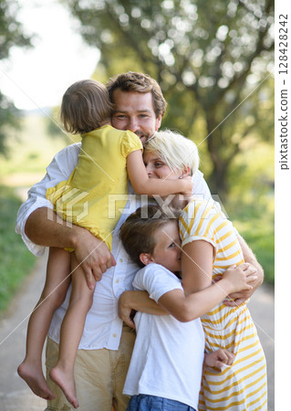 Portrait of young family with two kids hugging. 128428242
