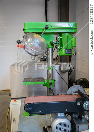 Green bench drill press and belt sander in workshop 128428337