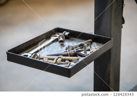 Mechanic tools resting on metal tray in garage workshop 128428343