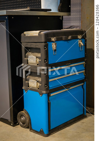 Blue rolling tool box with drawers and compartments standing in workshop 128428366