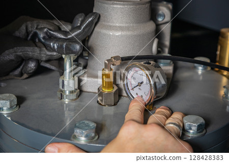 Technician adjusting pressure gauge on industrial equipment 128428383